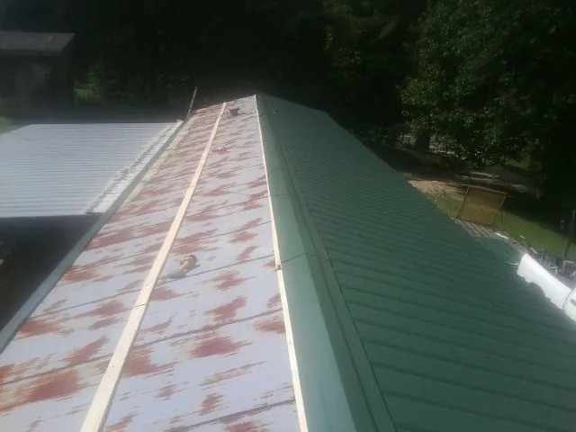 Old rusted panels beside newly installed green metal roofing — Wind Damage Roof Repair by Roofing Brothers in Granite Falls