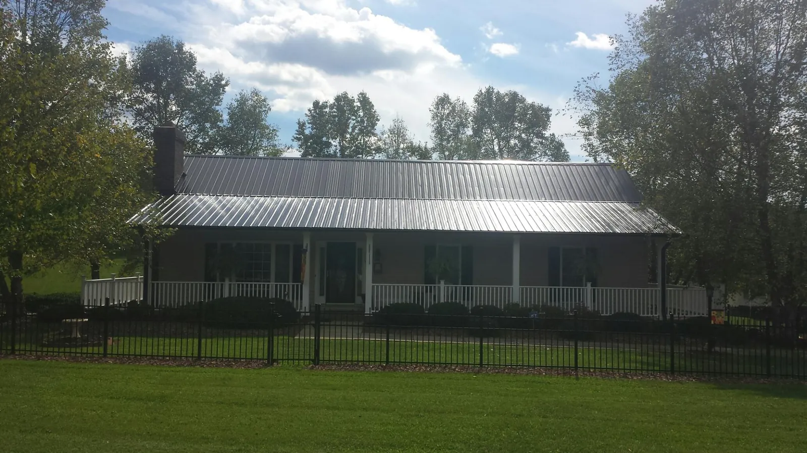 Gray metal roof on a brick ranch with a full width front porch — Gutter Guard Installation work by our crew in Granite Falls